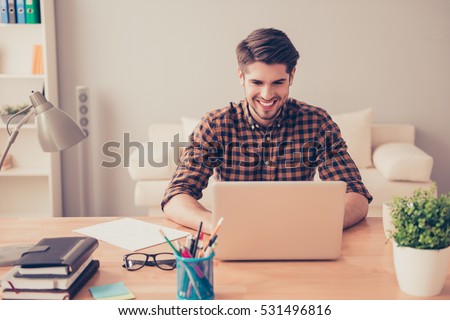 Portrait of happy young writer typing new book on laptop