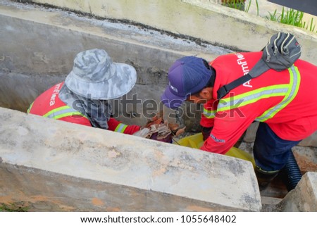 Muadzam Shah, Malaysia - March 22, 2018: Municipal workers "Alam Flora" uses sweepers and shovels to clean the garbage in the drain and put into the garbage bag.