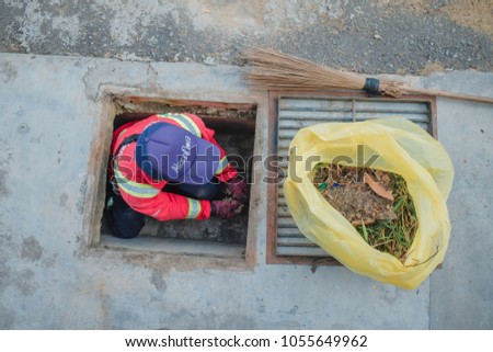 Muadzam Shah, Malaysia - March 22nd, 2018: Municipal worker "Alam Flora" uses sweepers and shovels to clean the garbage in the drain and put into the garbage bag.