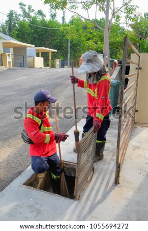 Muadzam Shah, Malaysia - March 22nd, 2018: Municipal workers "Alam Flora" uses sweepers and shovels to clean the garbage in the drain and put into the garbage bag.