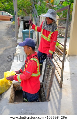 Muadzam Shah, Malaysia - March 22nd, 2018: Municipal workers "Alam Flora" uses sweepers and shovels to clean the garbage in the drain and put into the garbage bag.