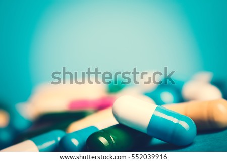 Medicine green and yellow pills or capsules on blue background with copy space. Drug prescription for treatment medication. Pharmaceutical medicament, cure in container for health. Antibiotic