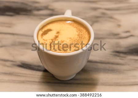 Top view a cup of Giang egg coffee in Hanoi on marble table. Since 1946 the coffee is dripped and brewed in a small cup with filter then addition of well-whisked mixture yolks and other ingredients.