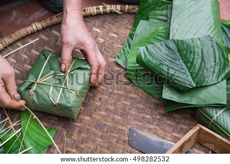 Hand wrapping Chung Cake in square shape with long node string split from bamboo. It is wrapped as tight as possible to keep cake from mold or spoiled. Traditional Vietnamese New Year (Tet) food.