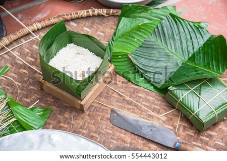 Chung Cake ingredients, tool preparation wrapping. Square shape wood mold with glutinous rice, split mung beans, chunks of pork shoulder, salt, pepper, ginger, bamboo, banana leaves, long node string.