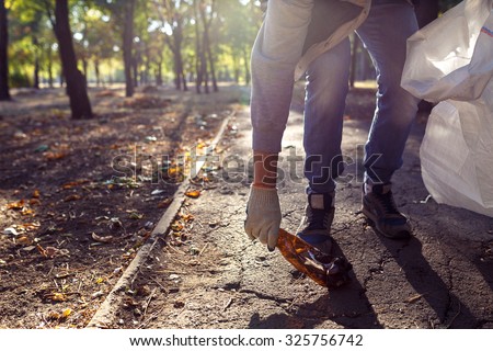 young man picking up trash outdoor. close up