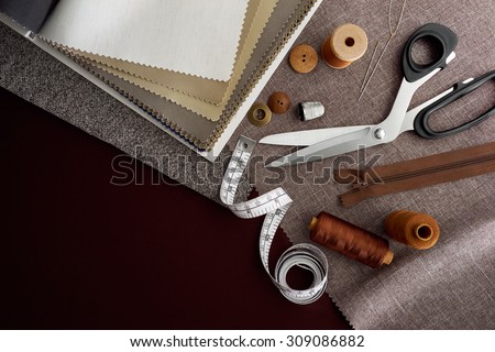 Scissor, buttons, zip, tape measure, thread and thimble on fabrics