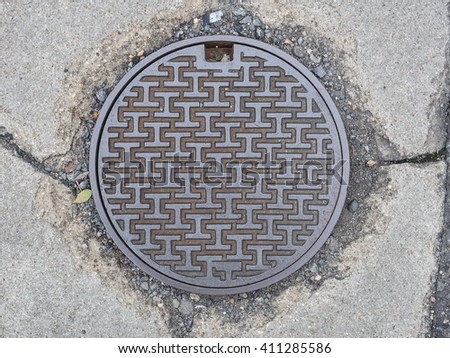 stock-photo-circle-steel-manhole-cover-on-concrete-street-in-japan-411285586.jpg
