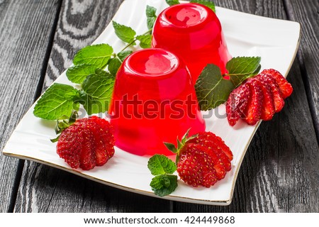 Tasty strawberry jelly and ripe strawberries on plate on a dark wooden table. Selective focus