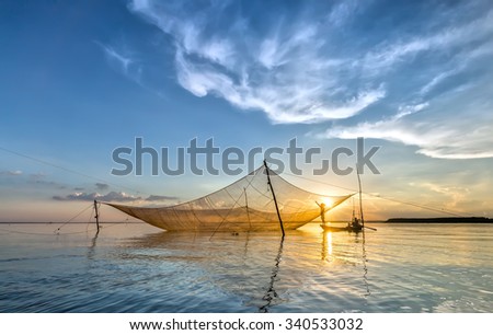 In Dong Nai, Vietnam - November 15th, 2015: fishermen mending their nets on his lift net as patch lifetime to grow more in the autumn afternoon in Tri An, Dong Nai, Vietnam