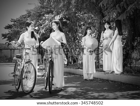 Ho Chi Minh City, Vietnam - September 13rd, 2015: Group student girls are chatting academic exchange with long dress and hat beautiful leaf corner schoolyard in Ho Chi Minh City, Vietnam