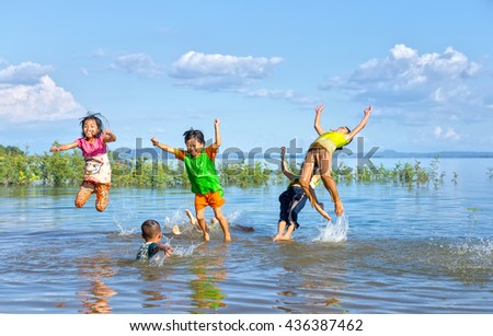 Dong Nai, Vietnam - November 15th, 2015: Children bathing in lake afternoon with dancing movements, flying directly into water as exciting games of childhood innocence rural areas in Dong Nai, Vietnam