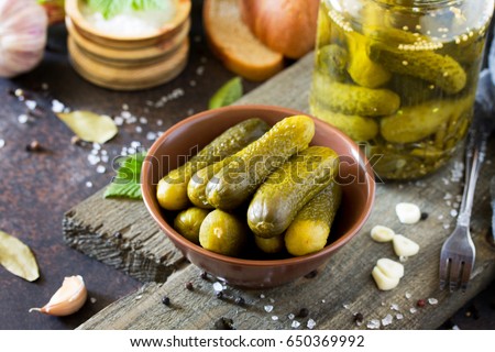 Marinated cucumbers gherkins. Pickles with mustard and garlic on a stone background.