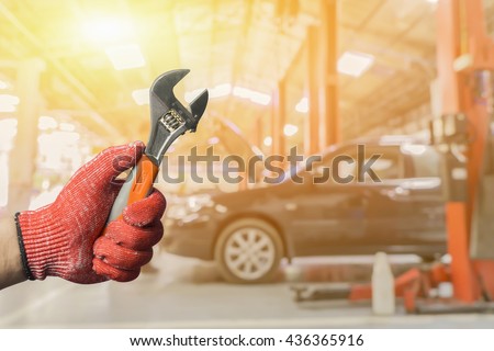 Car repairing,Hand of car technician auto mechanic with a wrench working in garage. Repair service ,car repair station.vintage tone