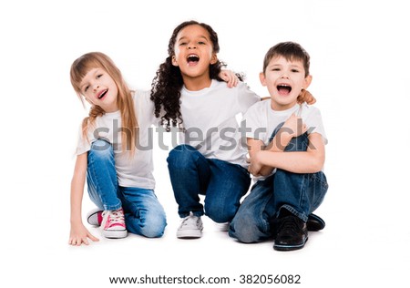 three funny trendy children laugh sitting on the floor