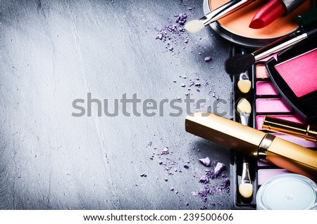 Various makeup products on dark background with copyspace