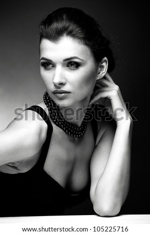 Black and white portrait of beautiful woman in black dress with pearl necklace