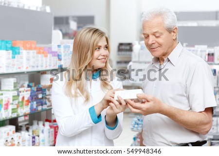 Helpful pharmacist. Cheerful young woman pharmacist assisting her senior client at the drugstore health medicine healthcare vitality helpful specialist drugstore shopping concept