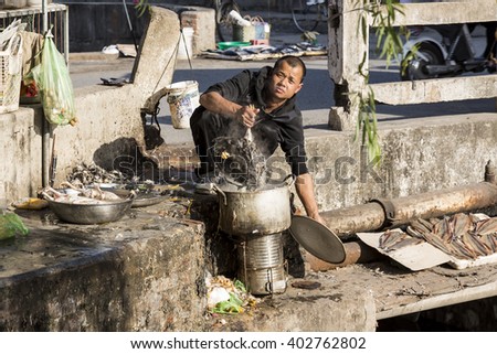 Hai Phong, Vietnam - February 2016. A man defeathering a Chicken in the street.
