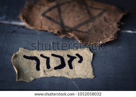 Closeup Of A Ragged Jewish Badge And Yellowish Piece Paper With The Word Yizkor Closeup Of A Ragged Jewish Badge And Yellowish Piece Paper With The Word Yizkor
