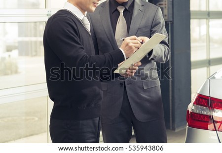 Seller or car salesman explaining the term and condition to the customer in car showroom