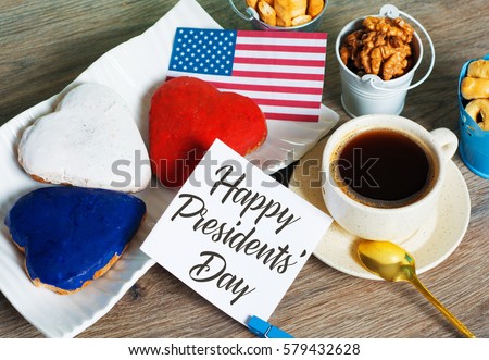 Heart shaped cookies color red, blue, white. Cup of coffee (tea), USA flag, decoration on old wooden table. Patriotic Breakfast Concept - Happy Presidents day. toned image