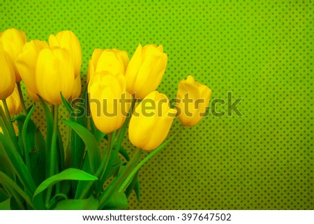 Yellow tulips on green background with space for message. Mother's Day background. Soft focus.