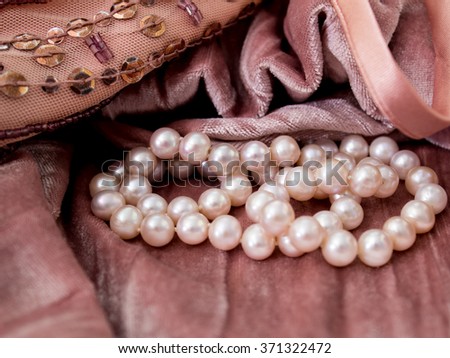 Photo of pink pearls on pink velvet fabric background with sequins and beads