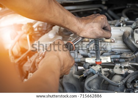 Hands of mechanic working in auto repair shop with sunlight