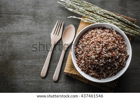 Brown/Coarse Rice with wooden spoon and fork, rice seed . Top view.