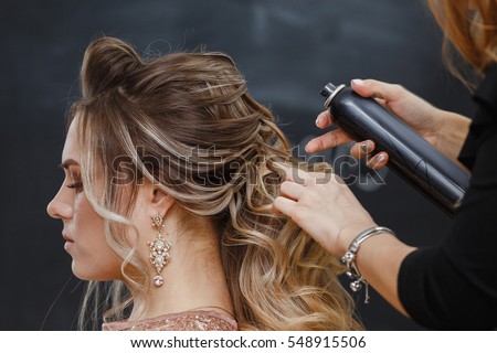 Hairdresser using hairspray on client's hair at salon