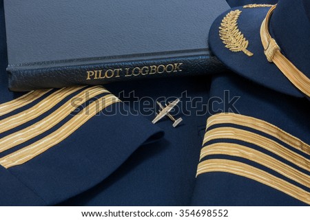 Pilot logbook with Captain 4 gold stripes on sleeves with Captain hat and Dash 7 pin.