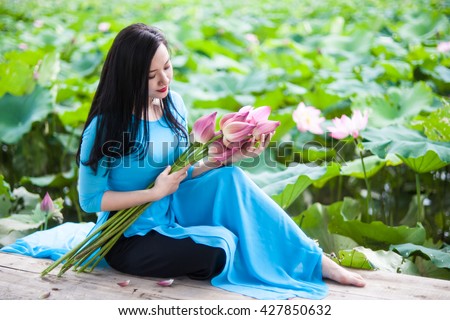 Beauty Vietnamese women wear traditional in lake of lotus.The Ao dai ( long-dress Vietnamese) is traditional costume of Vietnamese woman