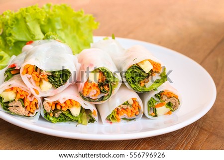 fresh vegetables spring rolls on white plate, wood table background.