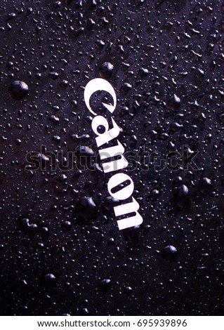 Water drops close-up on a photographic equipment logo CANON
