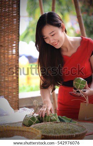 Ho Chi Minh ?ity, Vietnam - December 16, 2016: Young girl in red dress, smiling and choosing traditional cake (Banh Tet) for new year holidays