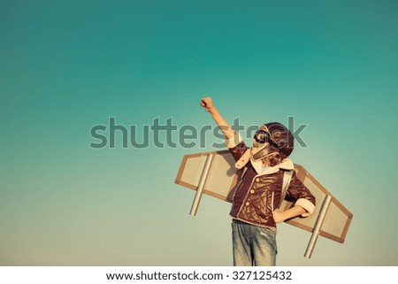 Kid pilot with toy jetpack against autumn sky background. Happy child playing outdoors