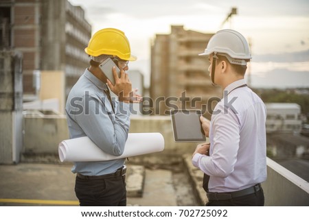 Smiling young architect or engineering builder in hard hat with tablet over group of builders at construction site, architect watching some a construction, business, building, industry, people concept