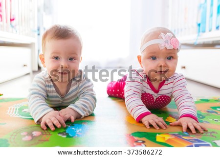 Baby boy and girl twins playing with the ball at home