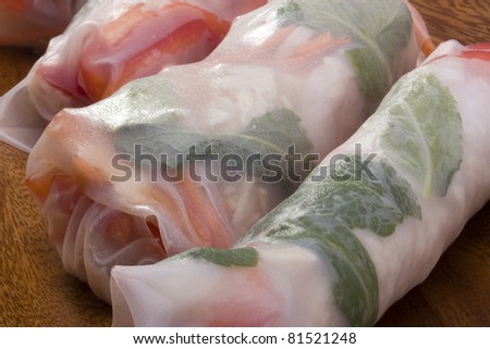 Asian spring rolls in rice paper on a wooden plate.