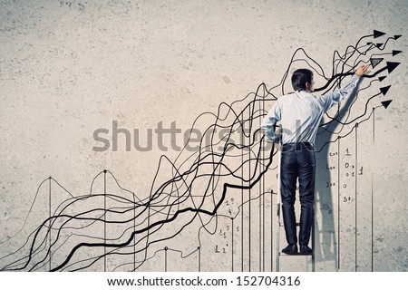 Back view image of businessman drawing graphics on wall