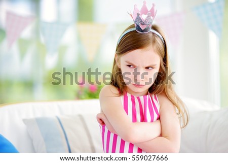 Moody little girl wearing princess tiara feeling angry and unsatisfied. Children tantrum concept.