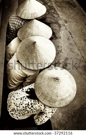 Vietnamese ladies sitting in a row showing their beautiful hats