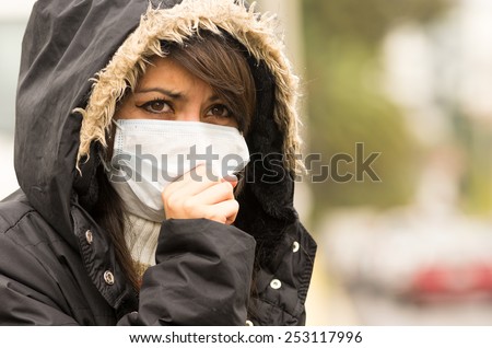 portrait of young girl walking wearing jacket and a mask in the city street concept of pollution