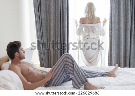 https://thumb9.shutterstock.com/display_pic_with_logo/487144/226829686/stock-photo-full-length-of-shirtless-young-man-looking-at-woman-standing-by-hotel-window-226829686.jpg