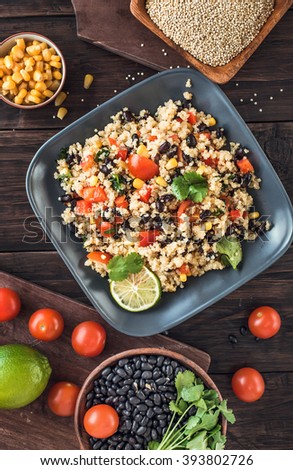 Black bean quinoa salad on rustic wooden background top view. Toned
