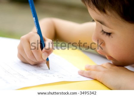 Young boy enjoying his his writing as part of homework, outdoors.