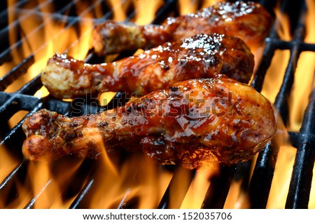 Chicken legs grilling over flames on a barbecue - stock photo
