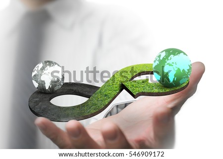 Green circular economy concept. Man's hand showing arrow infinity symbol with grass texture and two globes of different colors.