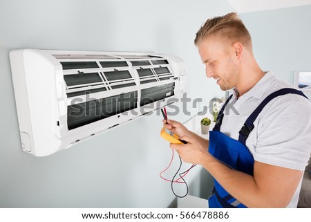 Male Electrician Checking Air Conditioner With Digital Multimeter